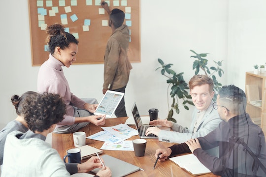 six business people meeting around a table using a cork board for marketing strategy